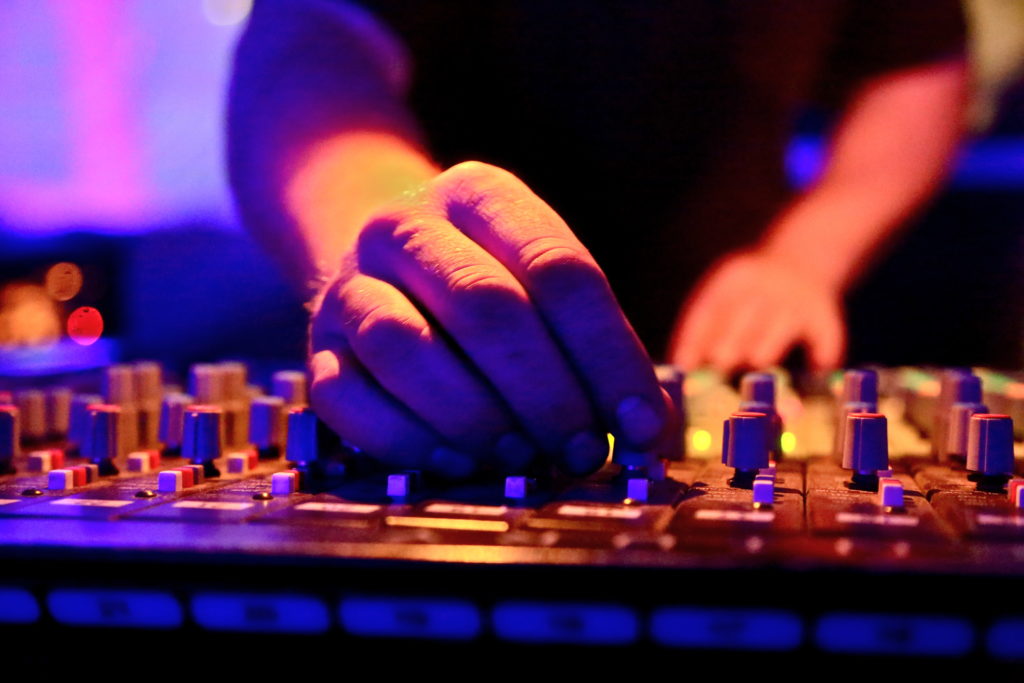 Hands under sunset lighting using a soundboard/mixer