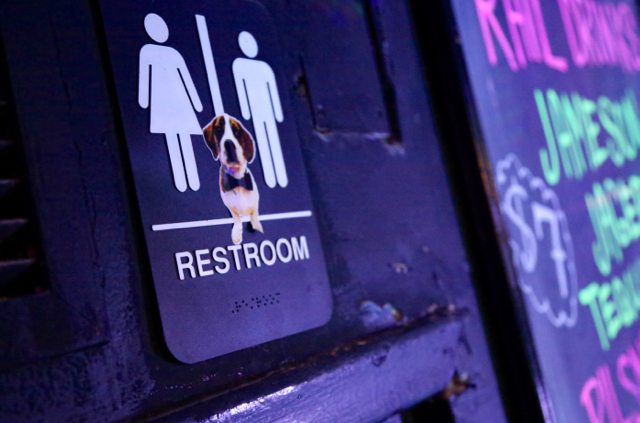 Picture of a standard gender neutral restroom sign that includes a sticker of a puppy