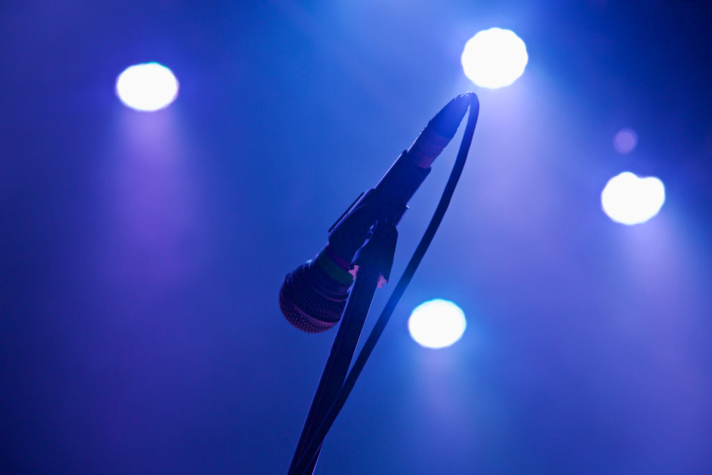 Microphone on stand on stage under a haze of purple lighting