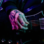 Tattooed hand playing an Epiphone SG guitar