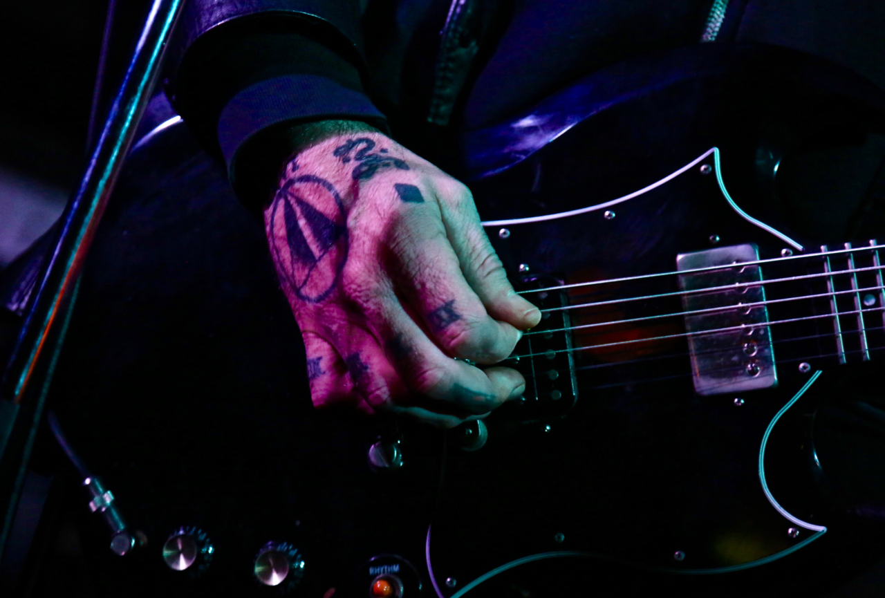 Tattooed hand playing an Epiphone SG guitar