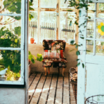 cottage with ivy hanging over white doors and a colorful chair sitting on old wooden floors