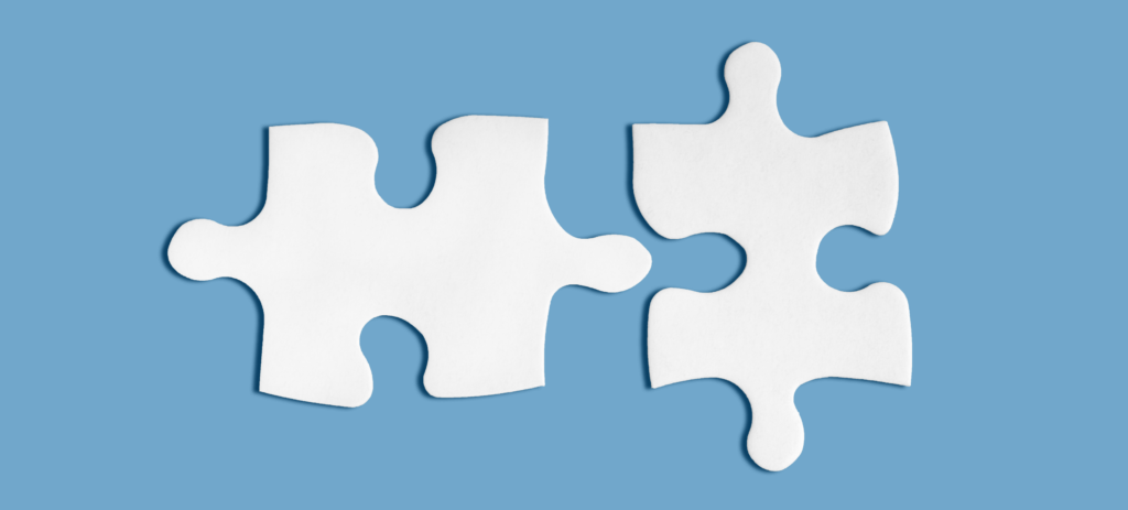 Photo of two white puzzle pieces nearly touching on a blue background