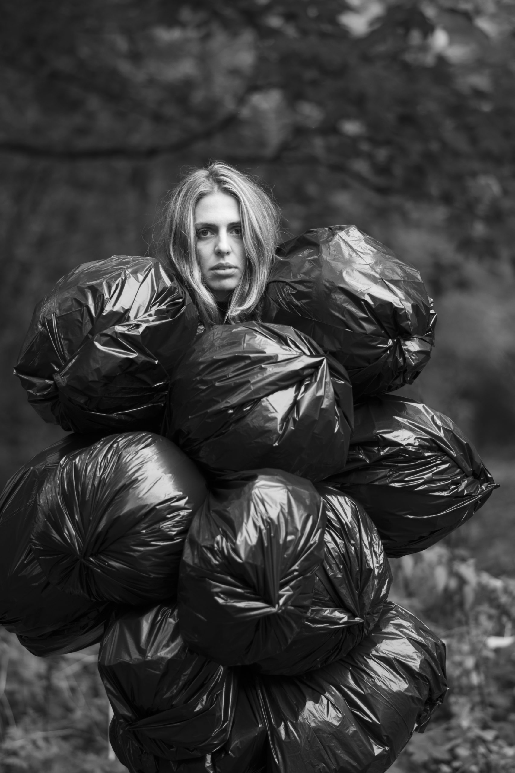 Woman staring at the camera with six black trash bags covering her body