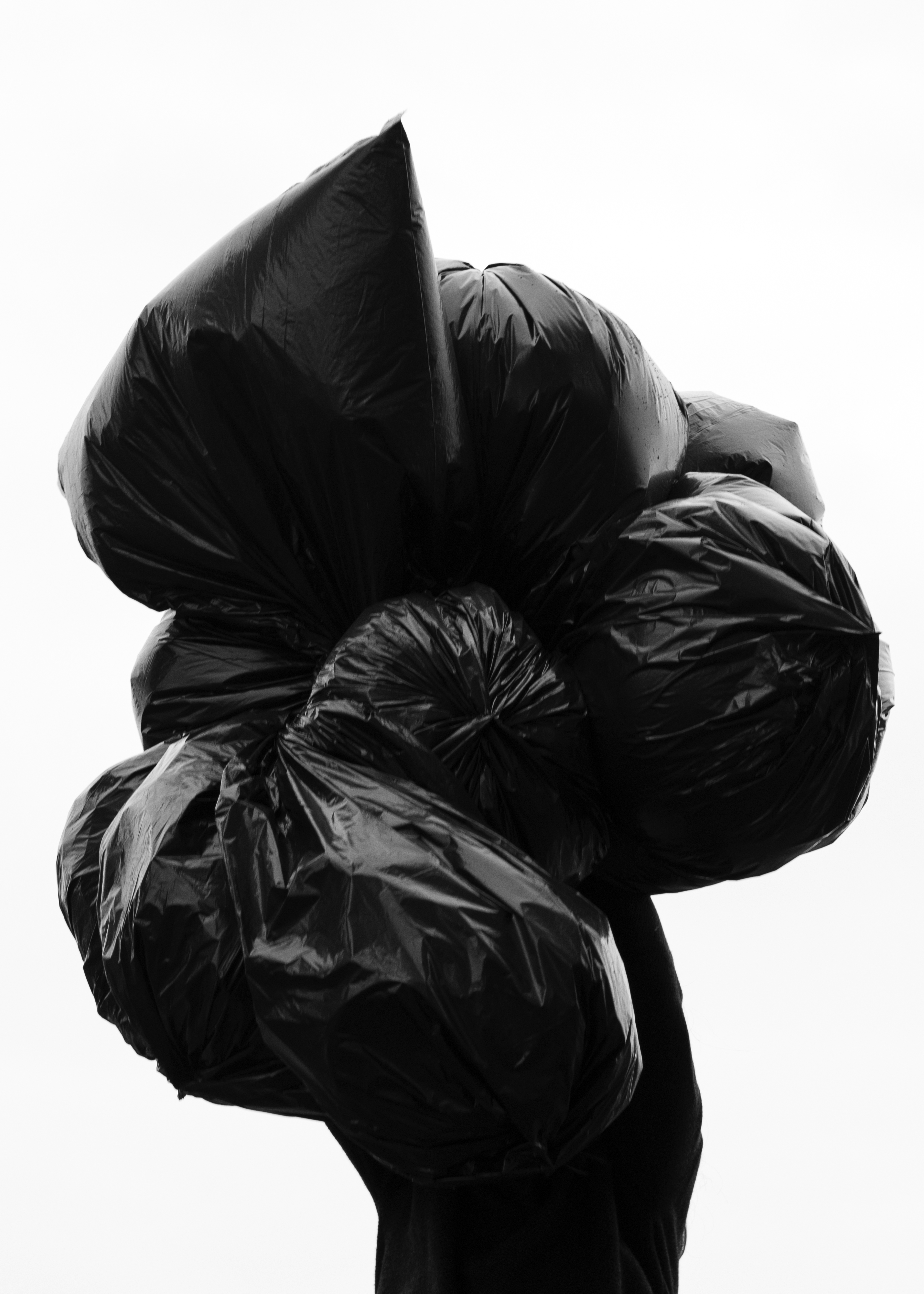 Photo of woman carrying giant pile of black trash bags