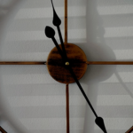 Photo of a large, metal roman numeral clock with shadows cast on the wall behind it