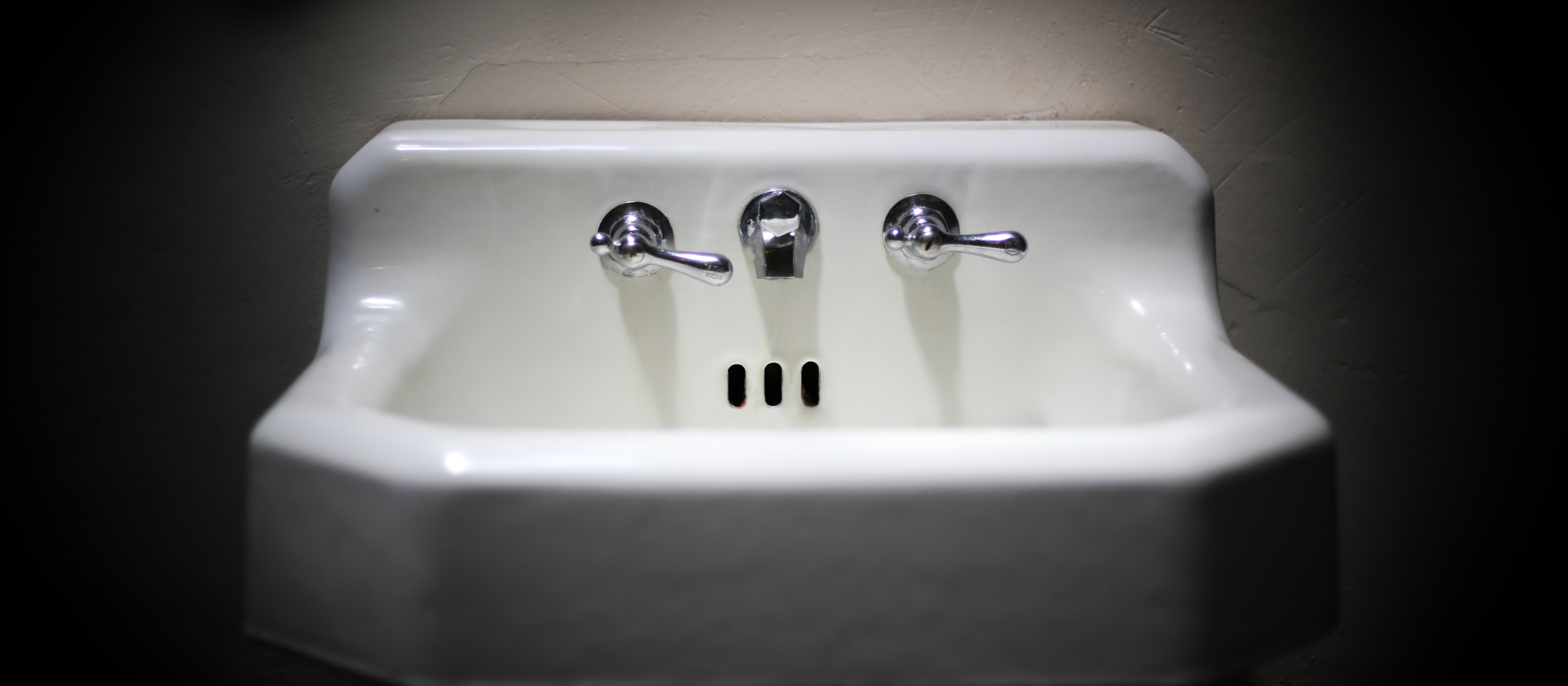 Photo of an old bathroom sink surrounded by darkness