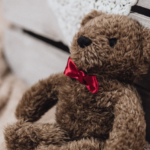 Photo of a dejected teddy bear lying next to a blanket