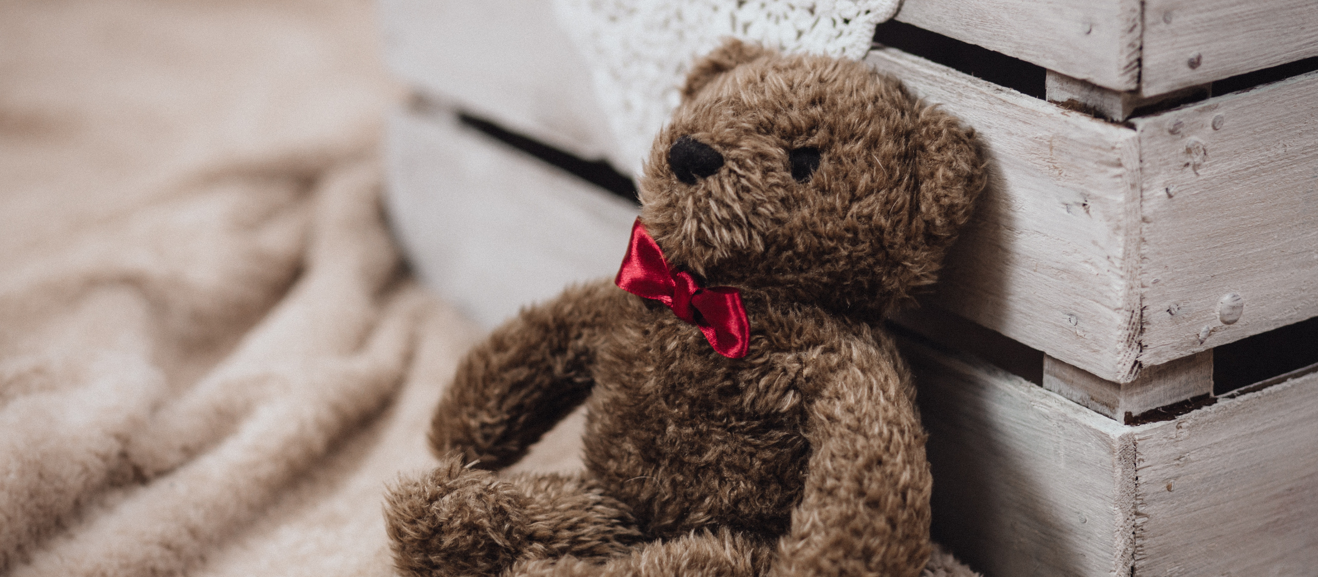 Photo of a dejected teddy bear lying next to a blanket