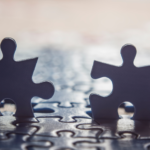 Photo of two puzzle pieces standing up atop a jigsaw puzzle